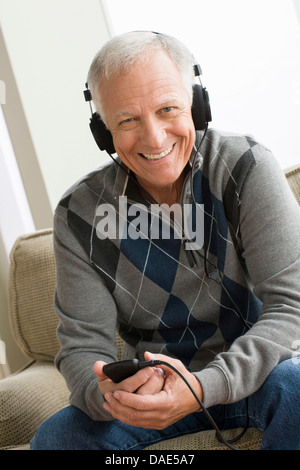 Senior man wearing headphones listening to music Banque D'Images