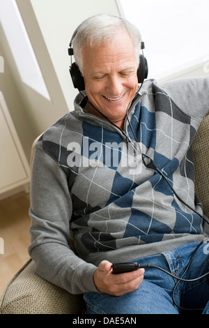 Senior man wearing headphones listening to music Banque D'Images