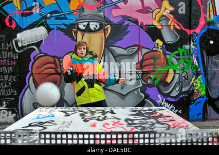 Garçon de douze ans à jouer au tennis de table en face de mur de graffiti, Allemagne, Berlin, Cologne Banque D'Images