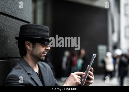 Portrait of man using digital tablet on city street Banque D'Images