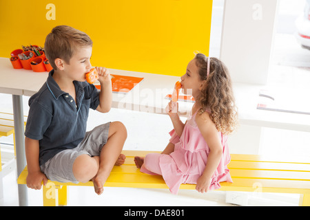 Brother and sister eating ice lollies sur l'établi à l'intérieur Banque D'Images