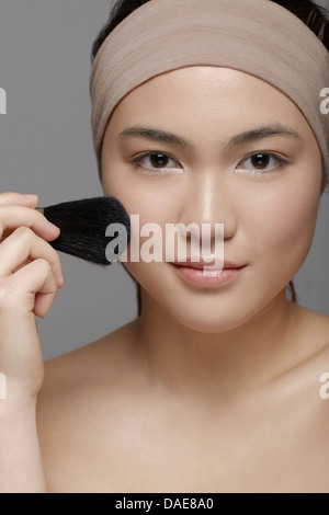 Young woman applying blush Banque D'Images