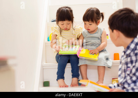 Les tout-petits de sexe féminin dans les escaliers avec carnet jeu Banque D'Images