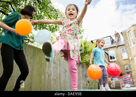 La mère et les filles jouant dans le jardin avec des ballons Banque D'Images