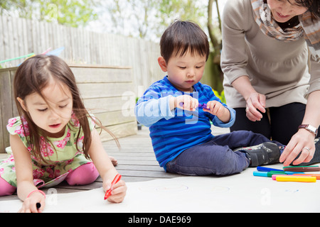 La mère et deux enfants dessin dans jardin Banque D'Images