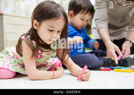 La mère et deux enfants dessin dans jardin Banque D'Images