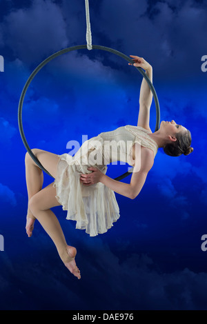 Aerialist performing on hoop against blue background Banque D'Images