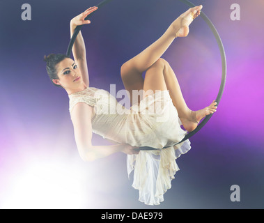 Aerialist poised on hoop contre fond violet Banque D'Images