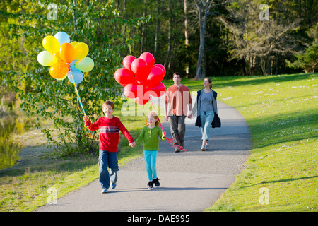 Balades en famille à travers park avec bouquets de ballons Banque D'Images