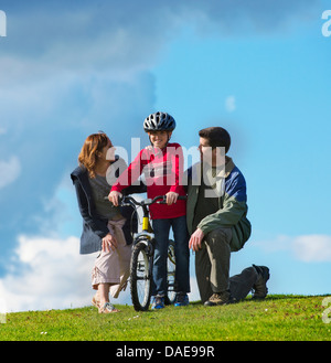 Mère et père fils encourageant à circuler à bicyclette Banque D'Images