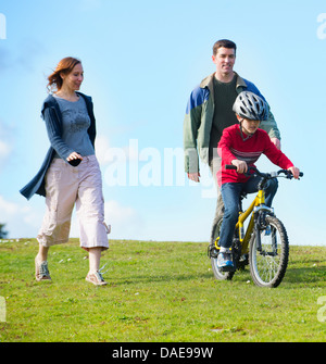 Les parents regardant son riding bicycle Banque D'Images