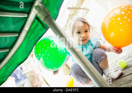 Jeune fille accroupi avec des ballons Banque D'Images