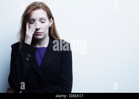 Studio portrait of young businesswoman se frottant les yeux Banque D'Images