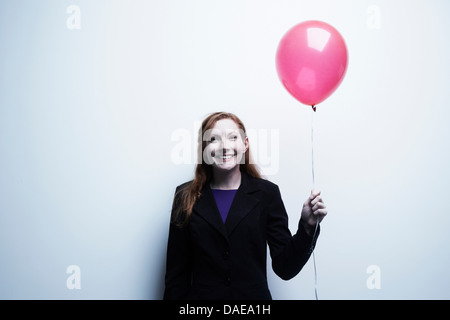 Studio portrait of young businesswoman holding red balloon Banque D'Images