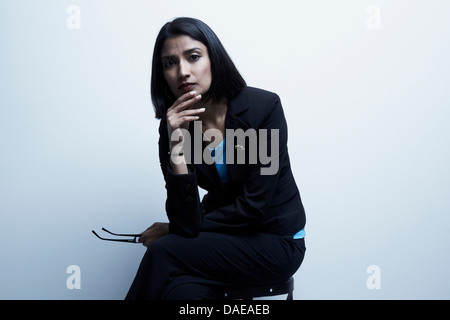 Studio portrait of businesswoman holding spectacles Banque D'Images