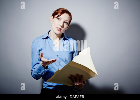 Studio portrait of young woman holding folder Banque D'Images