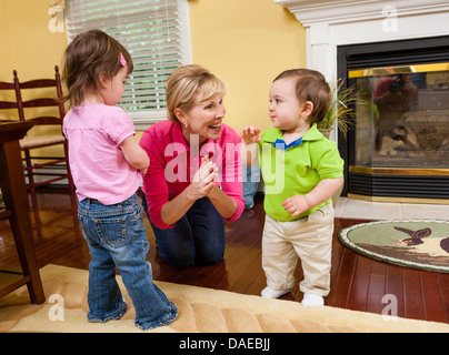 Grand-mère et ses petits-enfants jouant dans la salle à manger Banque D'Images