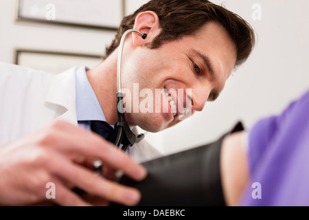 Young doctor with stethoscope et la pression artérielle du brassard sur le patient, Close up Banque D'Images