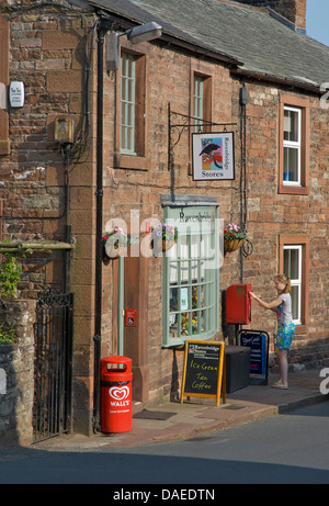 Jeune fille lettre d'affectation à l'épicerie du village à Kirkoswald, Eden Valley, Cumbria, Angleterre, Royaume-Uni Banque D'Images