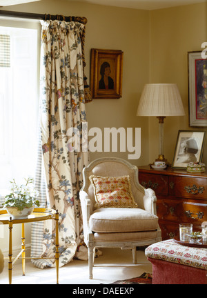 Fauteuil capitonné de style français en face de fenêtre avec des rideaux en pays salon Banque D'Images