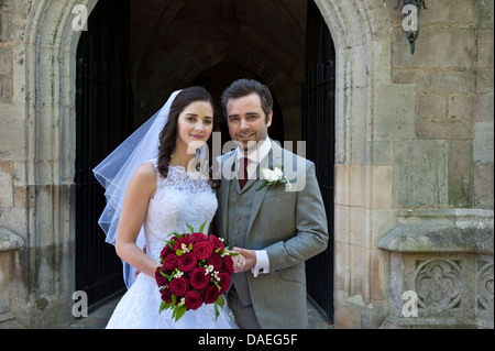 BRIDE & GROOM WHITE WEDDING BOUQUET ÉGLISE young Bride and Groom traditionnels mariés juste sur le pas de la porte de l'église gothique Banque D'Images