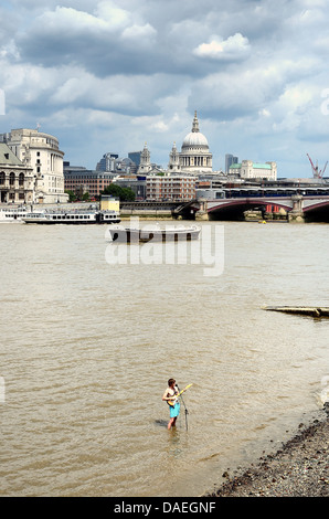 Musicien ambulant debout dans la Tamise avec une ville de Londres en arrière-plan Banque D'Images