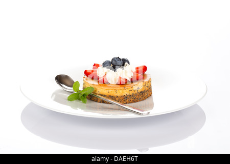 Gâteau au fromage aux fraises, bleuets, menthe et crème sur plaque blanche. Banque D'Images