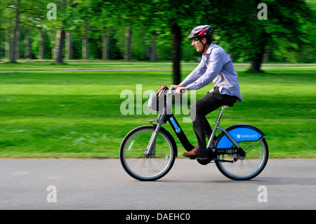 Un homme monté sur un vélo dans les jardins de Kensington, London, UK Banque D'Images