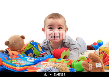 Bébé couché dans un tas de jouets et de pleurer Banque D'Images