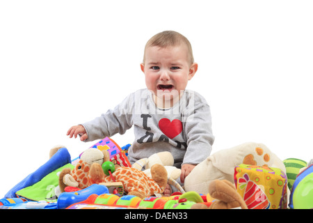 Baby sitting dans un tas de jouets et de pleurer Banque D'Images