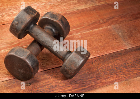 Une paire d'haltères rouillés fer vintage sur fond de bois grange rouge - concept de remise en forme Banque D'Images