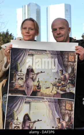 Le duo d'artistes danois résidant dans Berlin, appelé 'urrend", composé de Pia Bertelsen (L) et Jan Egesborg tenir leur nouvelle affiche satirique avec le titre "Ce n'est pas Tomé pour outrage ! Être escapiste.' en face de l'Fine Bank à Francfort, Allemagne, 30 novembre 2011. 150 exemplaires de cette affiche sont prévus pour être placés dans le quartier des banques et à Londres. Photo : AArn Banque D'Images