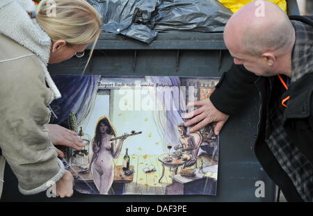 Le duo d'artistes danois résidant dans Berlin, appelé 'urrend", composé de Pia Bertelsen (L) et Jan Egesborg stick leur nouvelle affiche satirique avec le titre "Ce n'est pas Tomé pour outrage ! Être escapiste.' pour une corbeille à Francfort-sur-Main, Allemagne, 30 novembre 2011. 150 exemplaires de cette affiche sont prévus pour être placés dans le quartier des banques et à Londres. Photo : AArne Dedert Banque D'Images