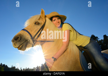 Islandic Horse, cheval islandais, Islande pony (Equus przewalskii f. caballus), de l'embrassé une jeune femme avec chapeau de paille, l'Allemagne, la Bavière Banque D'Images