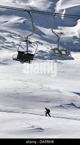 Un tourer ski promenades sous les télécabines d'un télésiège au Nebelhorn Oberstdorf, en Allemagne, près de la montagne, 11 décembre 2011. En raison du manque de neige les sports d'hiver saison démarre lentement dans la région de l'Allgaeu. Seulement quelques pistes de ski sont ouvertes. Photo : Karl Josef OPIM Banque D'Images