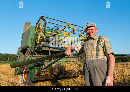 Agriculteur en face de son ancienne moissonneuse-batteuse, dans le champ de céréales, de l'Allemagne Banque D'Images