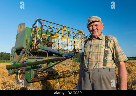 Agriculteur en face de son ancienne moissonneuse-batteuse, dans le champ de céréales, de l'Allemagne Banque D'Images