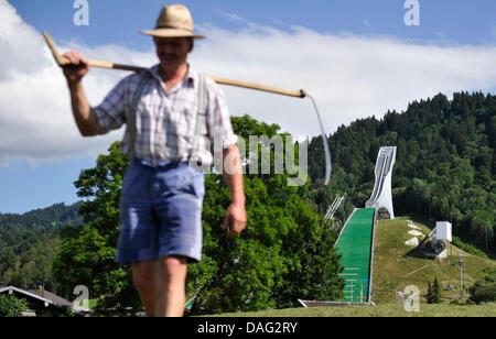 (Afp) un fichier photo datée du 09 août 2010 d'un agriculteur à marcher avec une faux en face de la piste de saut à ski olympique de Garmisch-Partenkirchen. L'Allemagne. Photo : Marc Mueller Banque D'Images