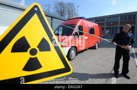 Un compteur Geiger est tenu à l'avant d'un signe d'avertissement de radioactivité dans Freiburg, Allemagne, 15 mars 2011. Photo : Patrick Seeger Banque D'Images