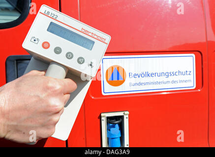 Un compteur Geiger est tenu à l'avant d'un signe d'avertissement de radioactivité dans Freiburg, Allemagne, 15 mars 2011. Photo : Patrick Seeger Banque D'Images