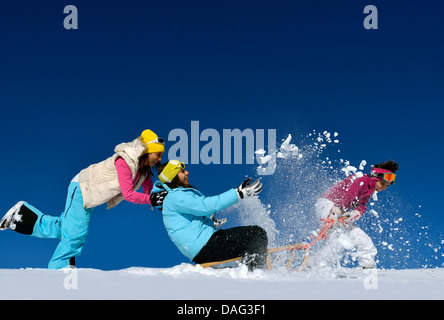 Trois adolescentes avec un traîneau de jouer dans la neige, France Banque D'Images