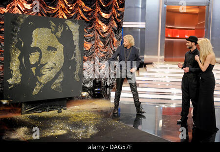 Co-modérateur Michelle Huntziker (r) et modérateur Thomas Gottschalk (l) regardez comme artiste français Michael Raivard construit une sculpture de Gottschalk de la colle et de sable pendant l'émission de télévision allemande "Wetten, dass... ?' à Augsburg, Allemagne, 19 mars 2011. C'est la 194e édition de la plus grande émission de télévision. Photo : Joerg Koch Banque D'Images