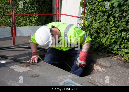 Un technicien en télécommunications BT Openreach travaillant dans un trou sur la route, Southport, Merseyside, Royaume-Uni Banque D'Images