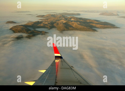 Vue depuis un avion qui se profile au sommet de montagnes hors de la couverture nuageuse, la Norvège, Troms, Tromsoe Banque D'Images