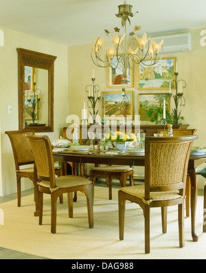 Chandelier en métal orné de fauteuils rembourrés et d'un mobilier en bois set de table pour le déjeuner dans la salle à manger jaune Banque D'Images