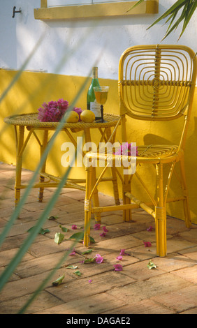 Close-up de canne peints en jaune sur table et chaise de terrasse pavée de briques de villa portugaise Banque D'Images