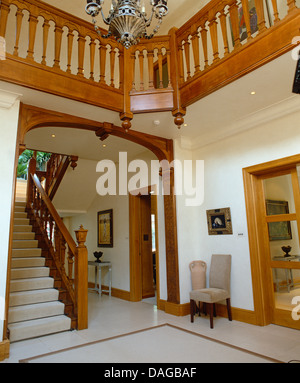 Tapis blanc sur l'escalier en bois en hauteur double hall avec rampes en bois sculpté à l'atterrissage Banque D'Images