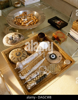 Close-up de collection d'objets dans le panier sur une table basse en verre avec plat de cacahuètes Banque D'Images