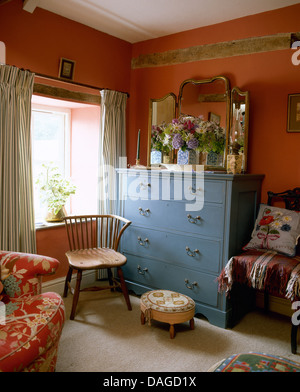 Miroir triptyque antique peinte en bleu sur une commode à côté fenêtre dans red cottage chambre avec mobilier chaise en bois Banque D'Images