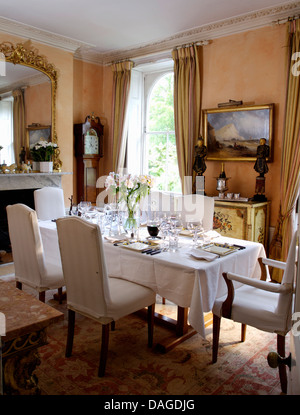 Meuble blanc couvre sur des chaises à table pour déjeuner avec un chiffon en lin blanc pays rose salle à manger avec miroir doré antique Banque D'Images